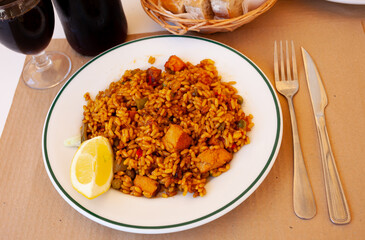 Sticker - Traditional Spanish dish is Paella with meat, made from rice with saffron and vegetables, decorated with a slice of lemon