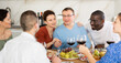 © JackF - Group of friends of different nationalities enjoying informal dinner and wine at kitchen table, engaging in lively conversations