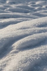 Close view of snow on the surface ground, bright white cold and reflective snow with sunlight shine to it slightly