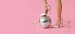 © Pixel-Shot - Female legs in high heel shoes, with glasses of champagne and disco ball on pink background with space for text. New year party concept