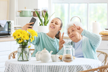 Canvas Print - Senior woman with her granddaughter taking selfie in kitchen