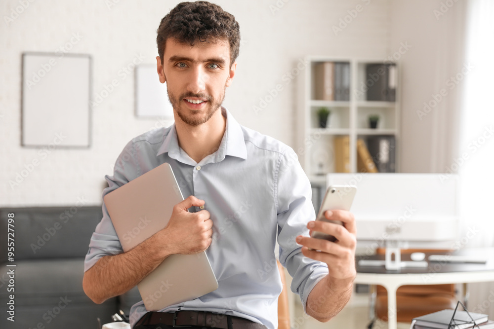 Young businessman working with mobile phone and laptop in office