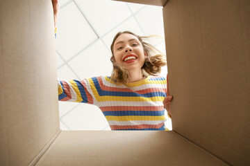 Canvas Print - Young woman with open parcel at home, view from inside