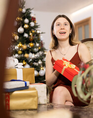 Wall Mural - Happy young woman prepares Christmas presents at home for guests, being in anticipation of the holiday