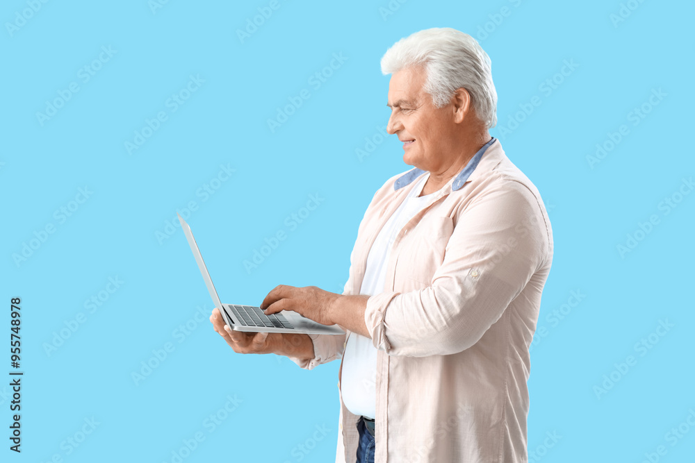 Senior man using laptop on blue background