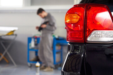 Car in auto repair shop with mechanic on a background