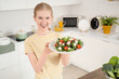 © Pixel-Shot - Happy young woman holding plate of tasty salad with feta cheese in kitchen