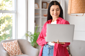 Wall Mural - Young woman using laptop at home