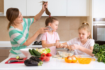 Mother and two daughters cooking in the kitchen and having fun, happy family and single mother concept 