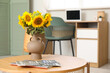 © Pixel-Shot - Vase with sunflowers and magazines on table in office