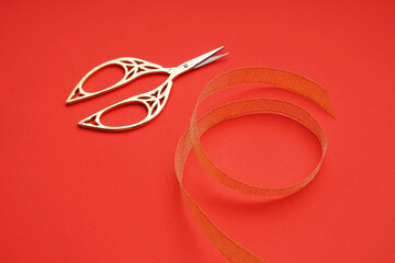 Wall Mural - Satin ribbon and scissors on red background