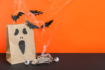 Sticker - Composition with paper shopping bag and decorations for Halloween on dark table against color background