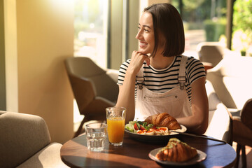 Canvas Print - Happy woman having tasty breakfast in cafe on sunny morning