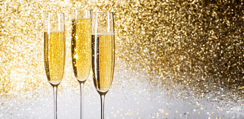 flutes with champagne or fizzy white wine on black background with blurred sparkles in the back