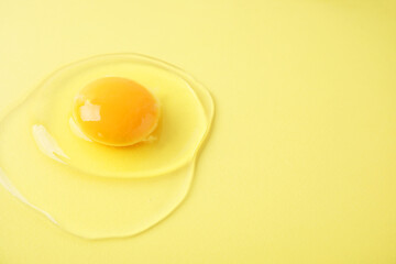 One raw egg on yellow background, closeup. Space for text