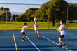 © Austockphoto - three children doing a netball training drill on blue playing surface outdoors