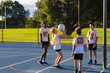 © Austockphoto - schoolchildren on outdoor court practising netball with short girl shooting