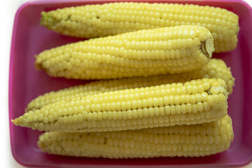 Wall Mural - Close-up of stacked boiled corns on red plastic plate, South Korea