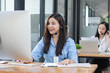© SOMKID - Young asian businesswoman with headset using desktop computer for customer support and online working in office, Call center helping for customers online concept.