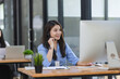 © SOMKID - Young asian businesswoman with headset using desktop computer for customer support and online working in office, Call center helping for customers online concept.