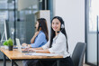 © SOMKID - Young asian businesswoman with headset using desktop computer for customer support and online working in office, Call center helping for customers online concept.