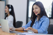 © SOMKID - Young asian businesswoman with headset using desktop computer for customer support and online working in office, Call center helping for customers online concept.