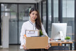 © SOMKID - Young asian woman employee with a storage box for the equipment after resigning and stressed from work.