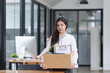 © SOMKID - Young asian woman employee with a storage box for the equipment after resigning and stressed from work.