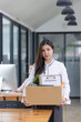 © SOMKID - Young asian woman employee with a storage box for the equipment after resigning and stressed from work.