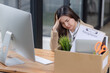 © SOMKID - Young asian woman employee with a storage box for the equipment after resigning and stressed from work.