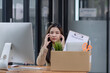 © SOMKID - Young asian woman employee with a storage box for the equipment after resigning and stressed from work.