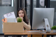 © SOMKID - Young asian woman employee with a storage box for the equipment after resigning and stressed from work.