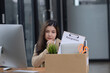 © SOMKID - Young asian woman employee with a storage box for the equipment after resigning and stressed from work.