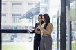 © SOMKID - Two Asian young businesswomen using tablet with analyzing financial charts in the modern office, Business financial documents and planning idea project concept.
