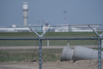 Airport security fence with control tower in background