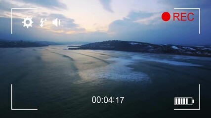 Poster - Camera interface animation over aerial view of serene coastal landscape at dusk
