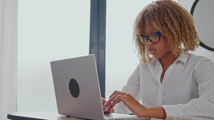 Aufkleber -  a woman sitting at a desk in an office, typing on a laptop. She is wearing a white shirt and glasses. the daytime, with natural light coming from a window behind her.