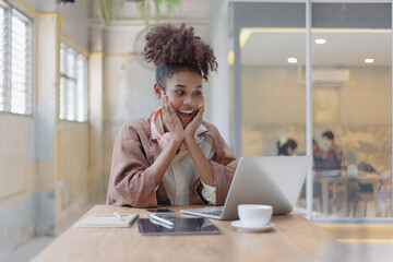 African American young woman using laptop computer with earphones.