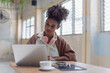 © SOMKID - African American young woman using laptop computer with earphones.