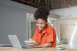 © SOMKID - About successful young woman concept. Excited African American woman sitting at working desk.