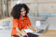 © SOMKID - About successful young woman concept. Excited African American woman sitting at working desk.