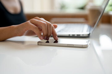 Wall Mural - A close-up image of a woman's finger touching on a smartphone screen on a table.