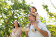 © KONSTANTIN SHISHKIN - Family walking together in park with son on father's shoulders