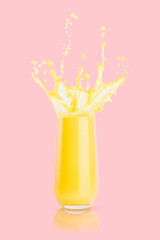 Orange juice in drinking glass with levitated drops, splashes, flows of juice on pink background. Vegetarian yellow fresh organic drink for advertising, label product, branding, flyer, poster, card.