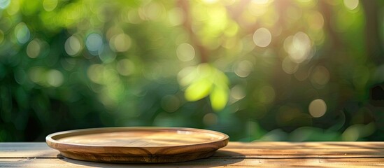 Wall Mural - Green blurred background with an empty wood plate top table allowing for copy space image