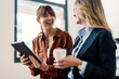 © Westend61 - Happy businesswoman holding tablet PC and standing with coworker at office