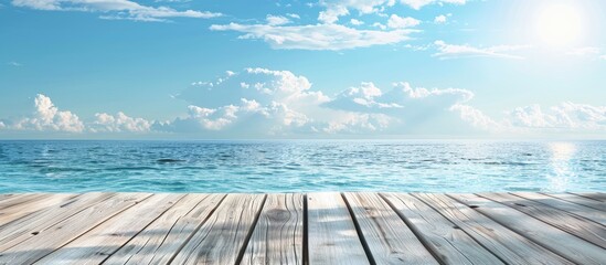 Summer seaside scene with a wooden pier under a clear blue sky a wooden table in the background and a product friendly copy space image by the azure sea