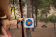 © Westend61 - Athlete woman with bow and arrow aiming on sport target board at forest
