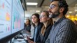 © bird_saranyoo - Colleagues gathered around a large monitor, discussing analytics and making data-driven decisions together.
