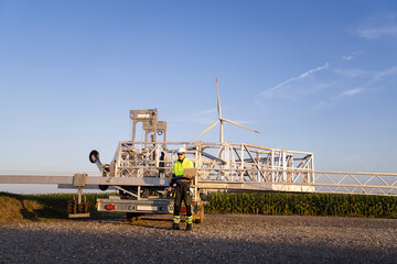 Engineer with laptop in front of wind turbine maintenance machine